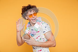 Excited young man in sunglasses holding coconut cocktail