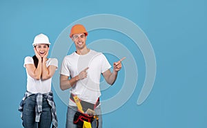 Excited Young Man And Woman In Hard Hats Pointing At Copy Space