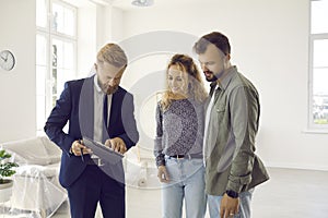 Excited young married couple going to sign deal with real estate agent during home inspection.