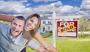 Excited Young Military Couple In Front of Home with Sold Sign