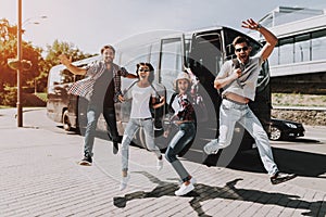 Excited Young People Jumping in front of Tour Bus