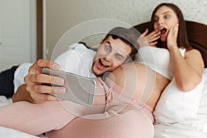 Excited young pregnant couple taking selfie