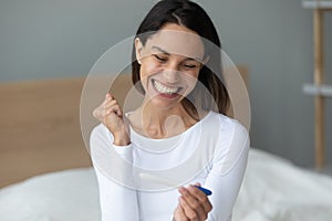 Excited young woman feel happy checking positive pregnancy test