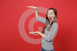 Excited young woman gesturing demonstrating size with copy space, keeping mouth wide open, looking surprised isolated on