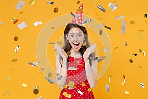 Excited young woman girl in red summer dress birthday hat isolated on yellow wall background studio portrait. Birthday