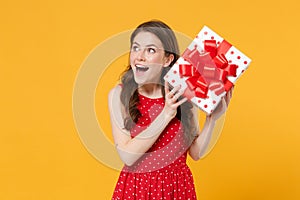 Excited young woman girl in red summer dress posing isolated on yellow wall background studio portrait. Birthday holiday