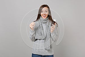 Excited young woman in gray sweater, scarf holding pour liquid medicine into spoon isolated on grey background. Healthy