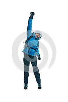 Excited young woman, hiker in jacket, gloves and goggles jumping isolated on white background. Comfortable and necessary