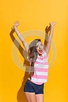 Excited Young Woman Holding Arms Raised And Looking Up