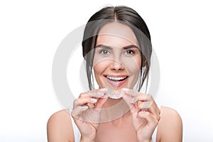 Excited young woman holding clear aligner photo