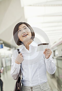 Excited young woman holding a train ticket in the train station, Beijing