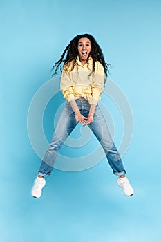 Excited young woman jumping up at orange studio