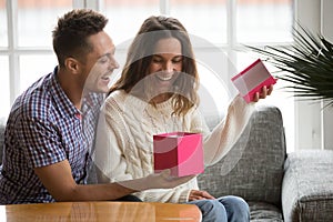 Excited young woman opening gift box receiving present from husband