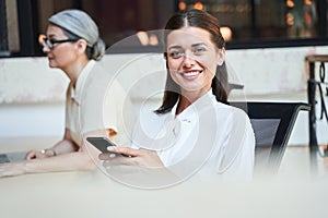 Excited young woman sitting in a chair with a phone