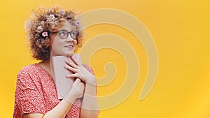 Excited young woman student or writer holding book and thinking. Curly hair full of spring flowers