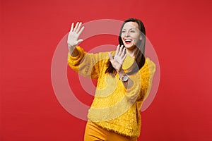 Excited young woman touch something like push click on button, pointing at floating virtual screen isolated on red wall