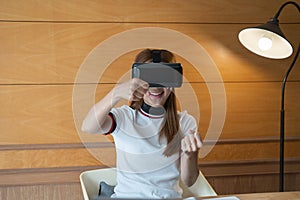 Excited young woman in VR goggles driving car in virtual reality. Lady screaming when turning virtual steering wheel