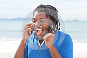 Exciting african american guy with dreadlocks at phone