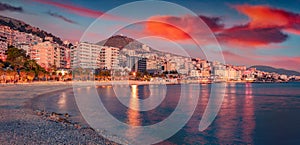 Exciting evening cityscape of Saranda port. Dramatic sunrise on Ionian sea.