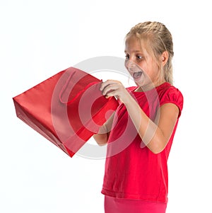 Exciting little girl looking inside shopping bag