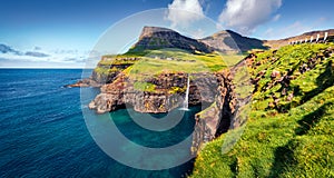 Exciting morning scene of Mulafossur Waterfall. Impressive summer view of Gasadalur village, Vagar, Faroe Islands, Denmark, Europe