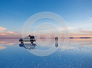 Exciting scenery of spacious Salar de Uyuni with couple and car photo
