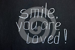 Exclamation on chalkboard `smile, you are loved`