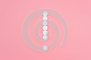 Exclamation mark from medical pills on a pink background. Treatment theme concept
