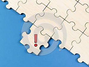 Exclamation mark symbol on jigsaw puzzle piece against blue background.