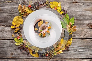 Exclusive autumn food on white plate decorated with flower, herbs, sauce and leaves, product photography for restaurant, beef or