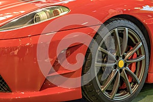 Exclusive sport car close up: car fender and bumper, headlight and wheel Red color