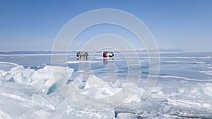 Excursion cars on the ice of lake Baikal. In the foreground is a large crack Toros. A winter journey through Russia