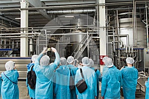 Excursion at the factory. People in protection, shoe covers, blue overalls stand and listen to a tour of the metal brewery. People