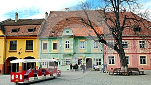 Excursion train through the main square of the Romanian city of Sighisoara awaiting tourists