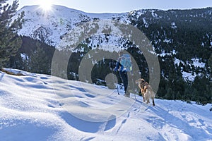 Excursionist man with his dog in a winter day with snow