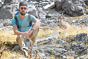 Excursionist man sitting next to an ibex