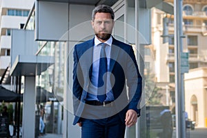 Executive businessman. Portrait of ceo near modern office in suit. Happy leader standing in front of company building.