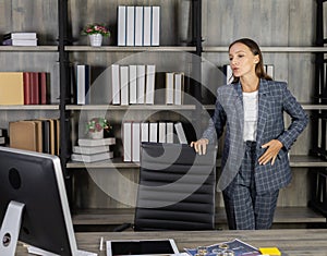 executive businesswoman communicate with team in online meeting, stand near desk, looks at computer in workplace