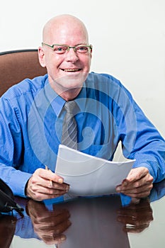 Executive at desk holding papers