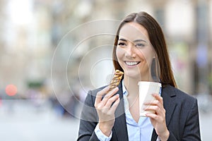 Executive holding snack bar and takeaway coffee in the street photo