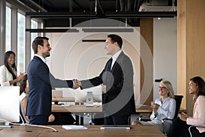 Executive manager shaking hand of successful employee at meeting