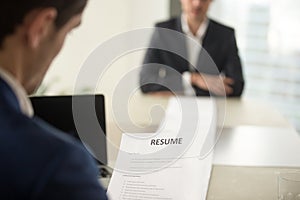 Executive reading cv during job interview, focus on resume, clos