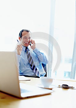 Executive smiling during discussion on phone. View of Business man sitting in office and talking on phone.