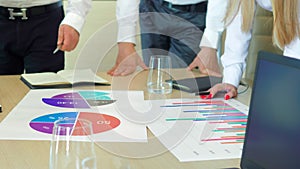 The executive team of business people discuss with colleagues the company's development strategy on the charts