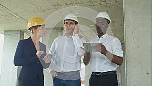 Executive team on construction site reviewing with tablet, smartphone, formal dressed people reading construction tablet