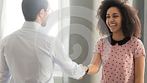 Executive, team leader shaking hand of successful diverse smiling employee