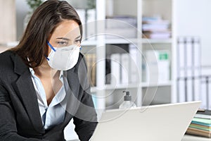 Executive wearing protective mask working on laptop
