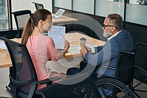 Executive in wheelchair and employee work at the office table