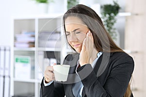Executive with toothache holding coffee at office photo