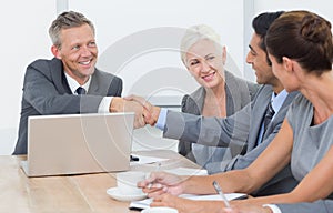 Executives shaking hands in board room meeting